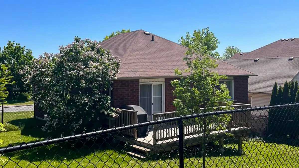 Backyard view of a finished asphalt shingle re-roof with deck, Peterborough region