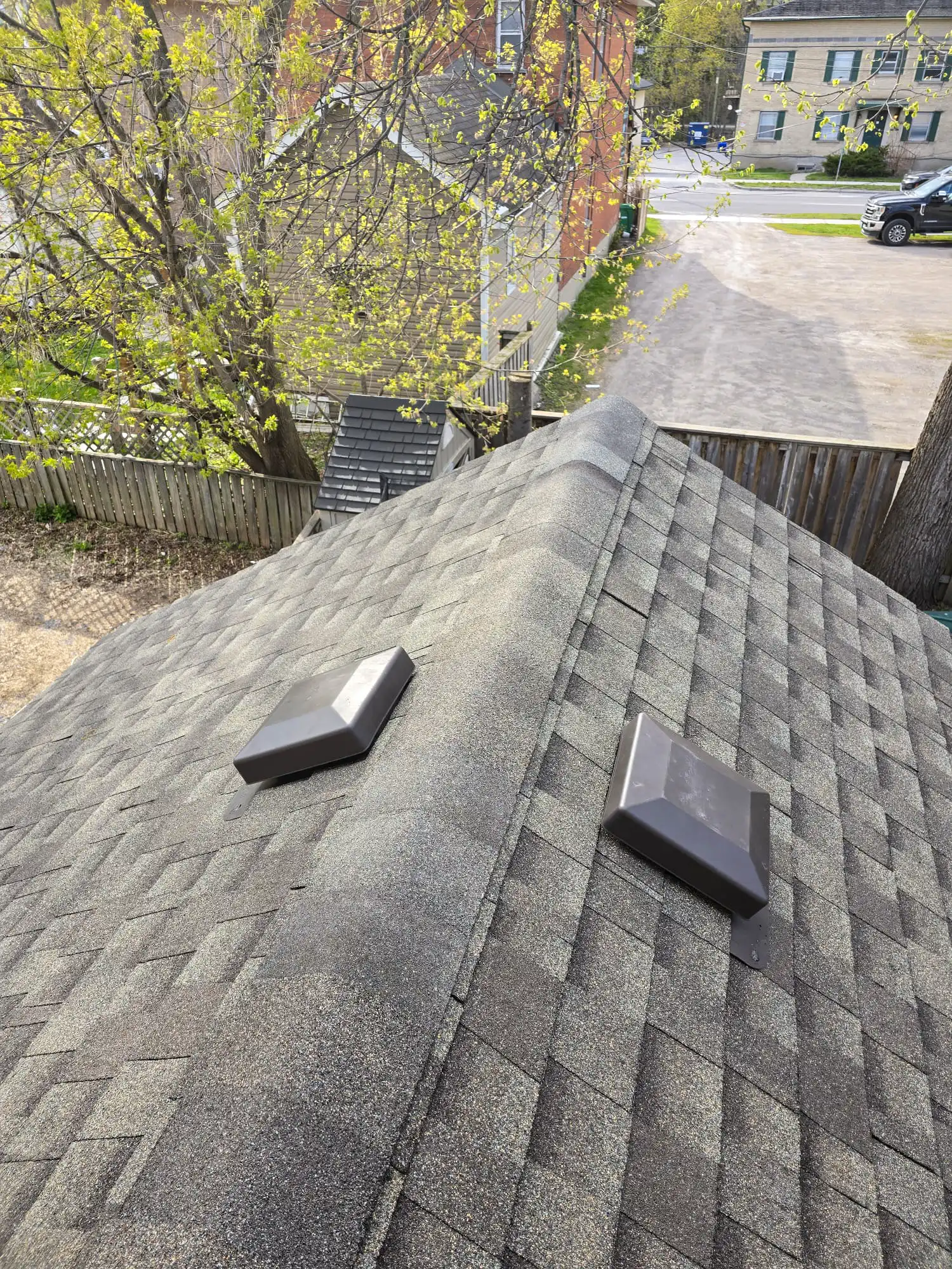 Completed asphalt shingle roof with new vents overlooking a Peterborough residential neighbourhood
