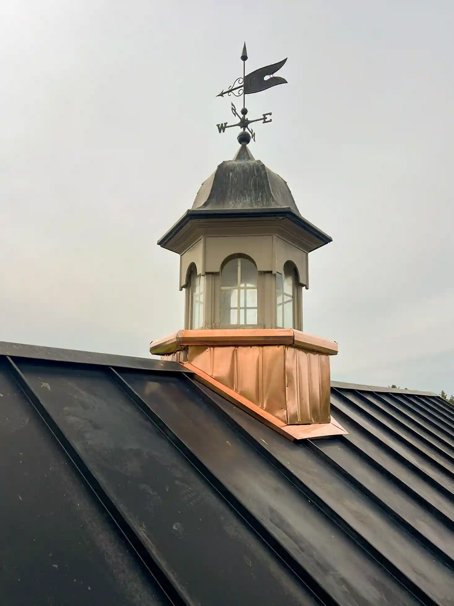Copper cupola base on standing seam metal roof on a cloudy day