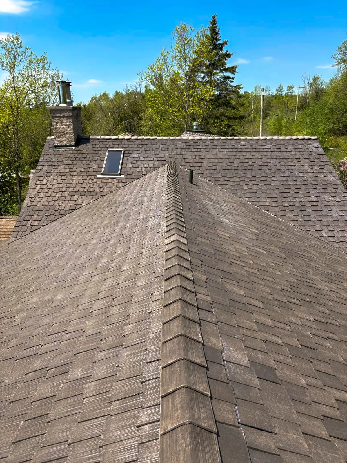 Finished Enviroshake composite shake roof ridge against a blue sky, installed by Bullarco in the Kawarthas